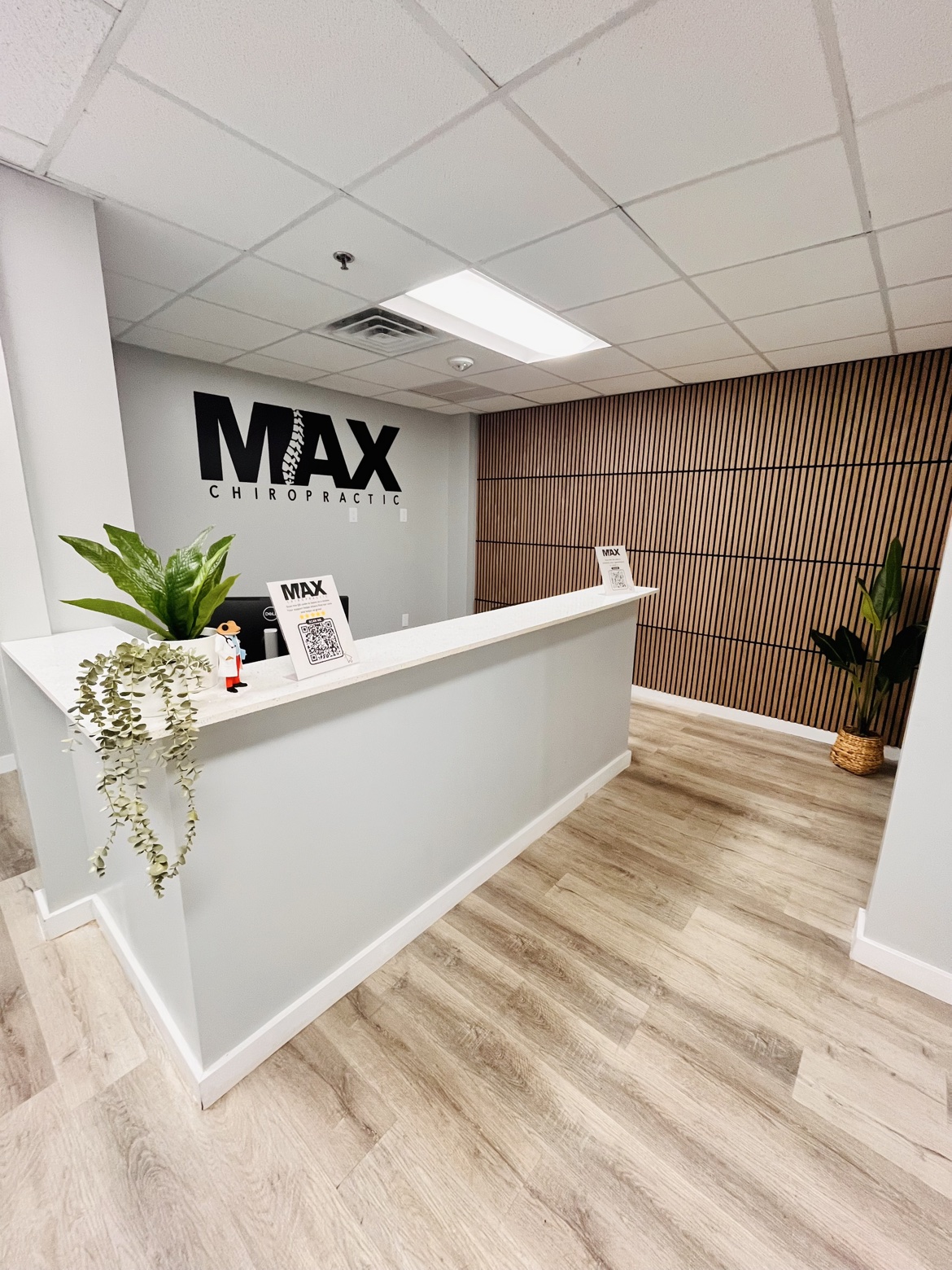 Bright modern reception area at Max Chiropractic Center with the clinic wall logo