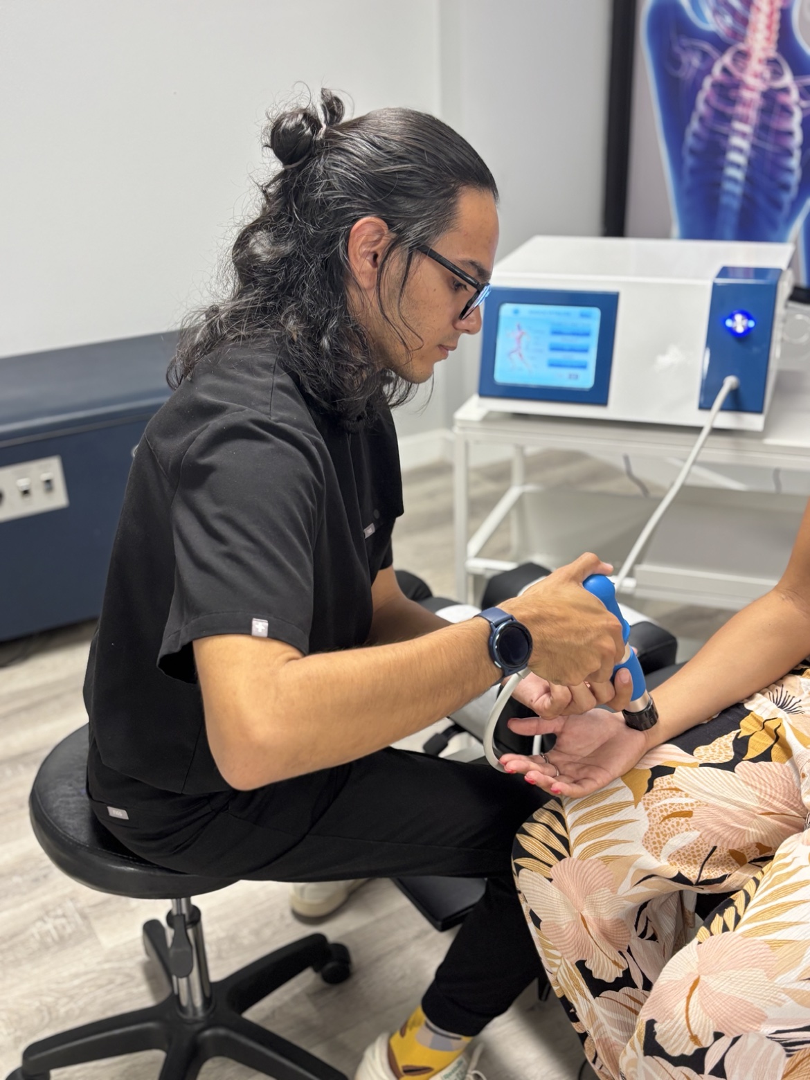 Max Chiropractic clinician providing shockwave therapy to a patient's wrist